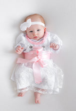 Lade das Bild in den Galerie-Viewer, Ein Baby in einem eleganten Babydirndl, Taufdirndl, Taufkleid aus Seide und Spitze von Anna Kaval, posiert auf einem weißen Untergrund, während es ein rosa Satinband trägt. Kinderdirndl, Taufdirndl.