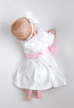 Lade das Bild in den Galerie-Viewer, Ein Baby von hinten in einem Babydirndl, Taufdirndl, Taufkleid aus Seide und Spitze von Anna Kaval, das eine rosa Schleife trägt, auf einem hellen Hintergrund. Kinderdirndl, Taufdirndl.