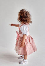Lade das Bild in den Galerie-Viewer, Seitenansicht eines kleinen Mädchens, das das Babydirndl/Taufdirndl/Taufkleid Traum aus Seide von Anna Kaval trägt und mit dem Finger auf etwas zeigt.