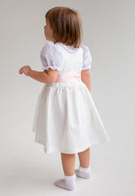 Lade das Bild in den Galerie-Viewer, Rückansicht eines Mädchens im Babydirndl/Taufdirndl/Taufkleid Rosalie von Anna Kaval. Das weiße Taufkleid Mädchen beeindruckt durch seine feine Verarbeitung und ist als Taufdirndl ideal für besondere Feierlichkeiten.