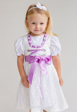 Lade das Bild in den Galerie-Viewer, Ein Mädchen in einem schönen Flieder Babydirndl von Anna Kaval, das eine feine Schnürung und ein bezauberndes Designs mit Puffärmeln aufweist. Das perfekte Taufdirndl für besondere Anlässe.