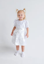 Lade das Bild in den Galerie-Viewer, Das kleine Mädchen in einem stylischen Baby Trachtenkleid zur Taufe von Anna Kaval, bestehend aus hochwertiger Bio-Baumwolle, mit dekorativen Details.