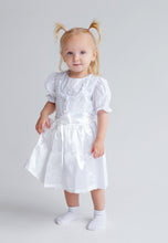 Lade das Bild in den Galerie-Viewer, Ein kleines Mädchen posiert in einem wundervollen Baby Trachtenkleid zur Taufe von Anna Kaval, aus weicher Bio-Baumwolle, passend für festliche Anlässe.