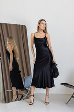 Lade das Bild in den Galerie-Viewer, Frau trägt elegantes schwarzes Satin-Midikleid aus 100% Viskose mit Spaghettiträgern und Wasserfall-Ausschnitt

